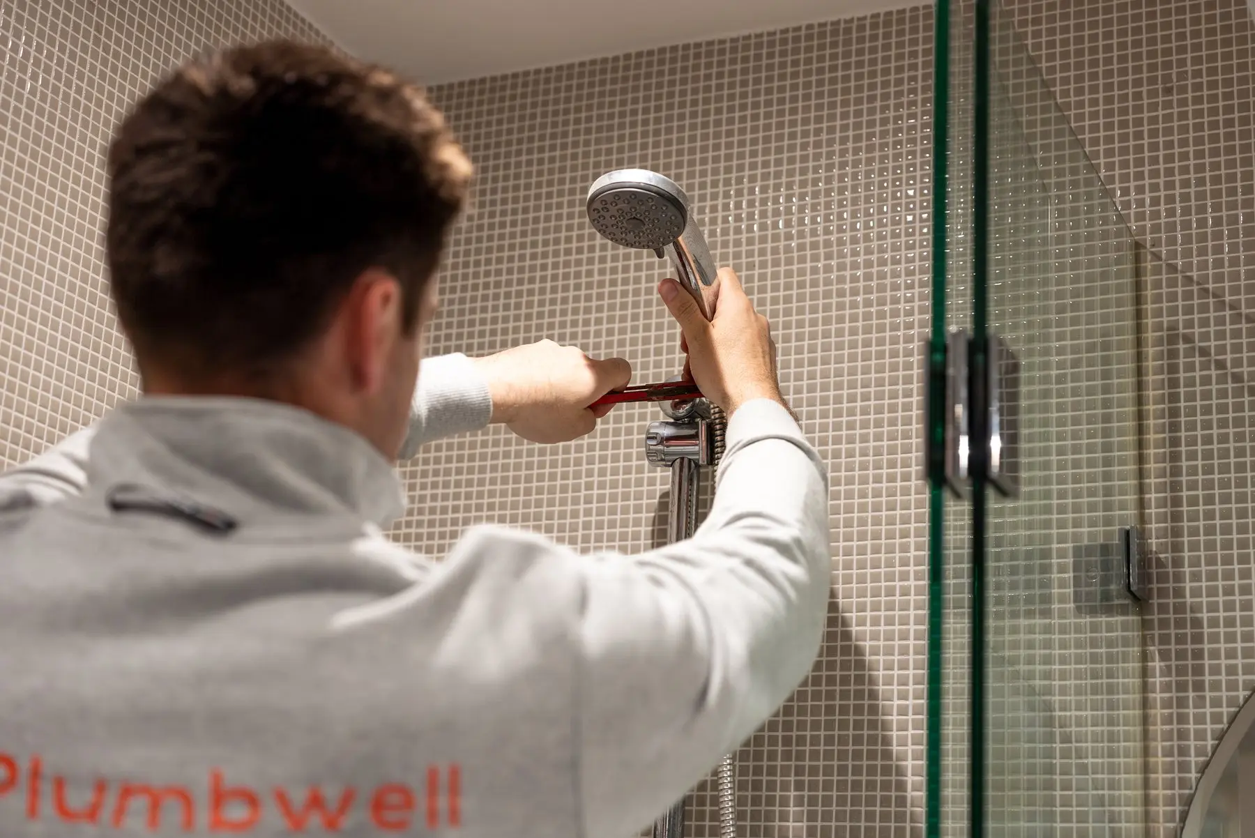 A Plumbwell plumber clearing a blocked shower drain